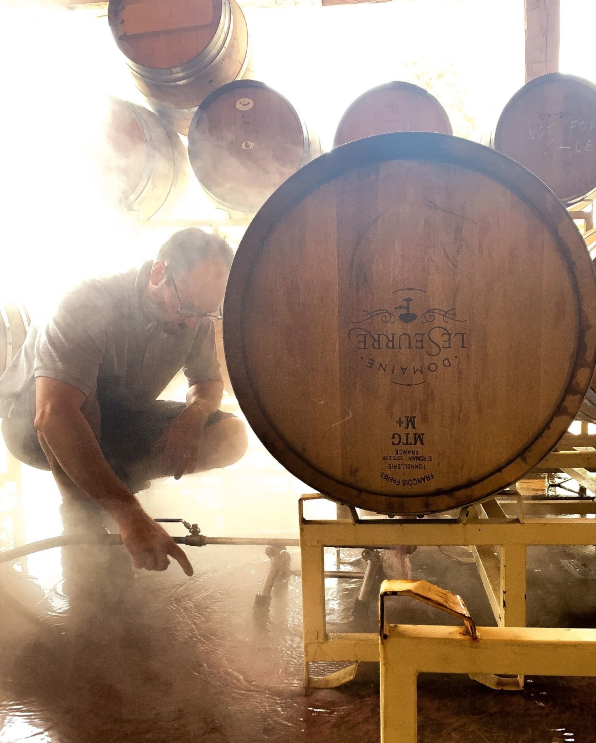 Sébastien steaming oak barrels in backlit morning light.