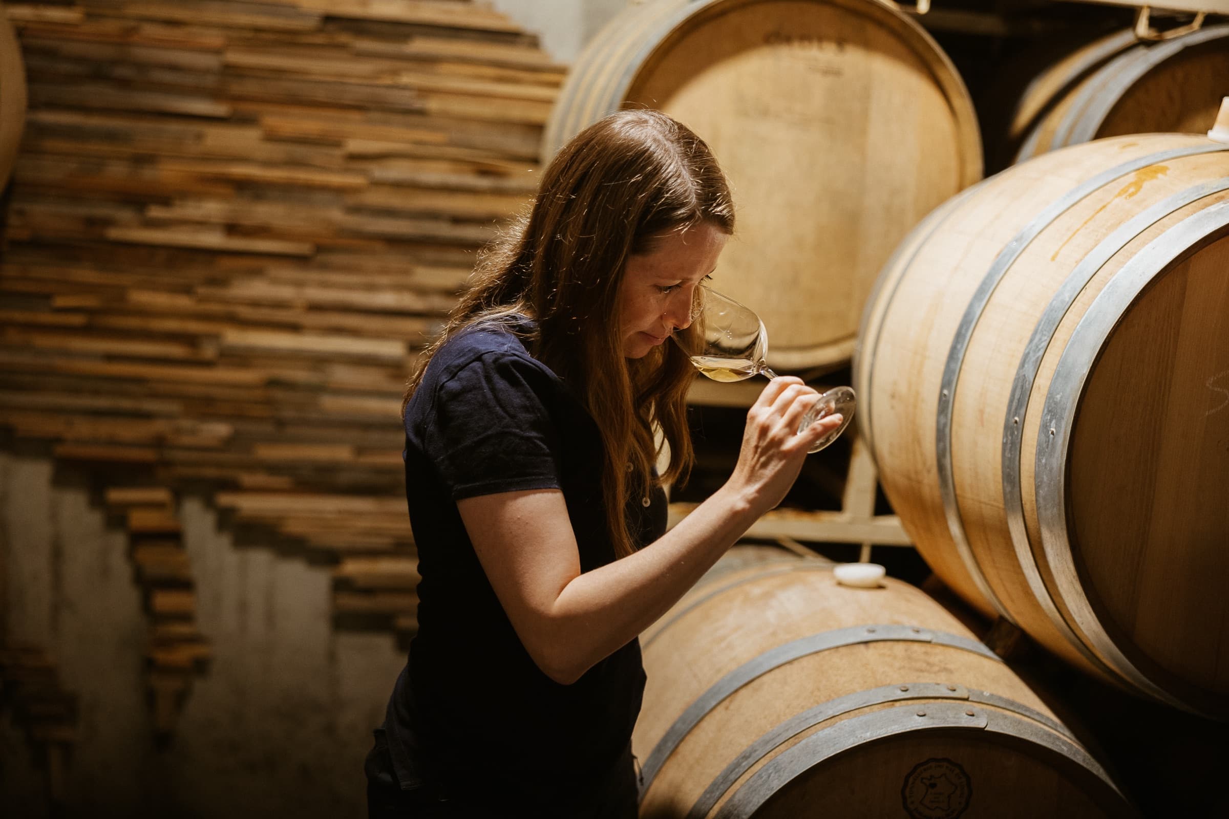 Céline LeSeurre nosing a glass of white wine drawn from the barrel.