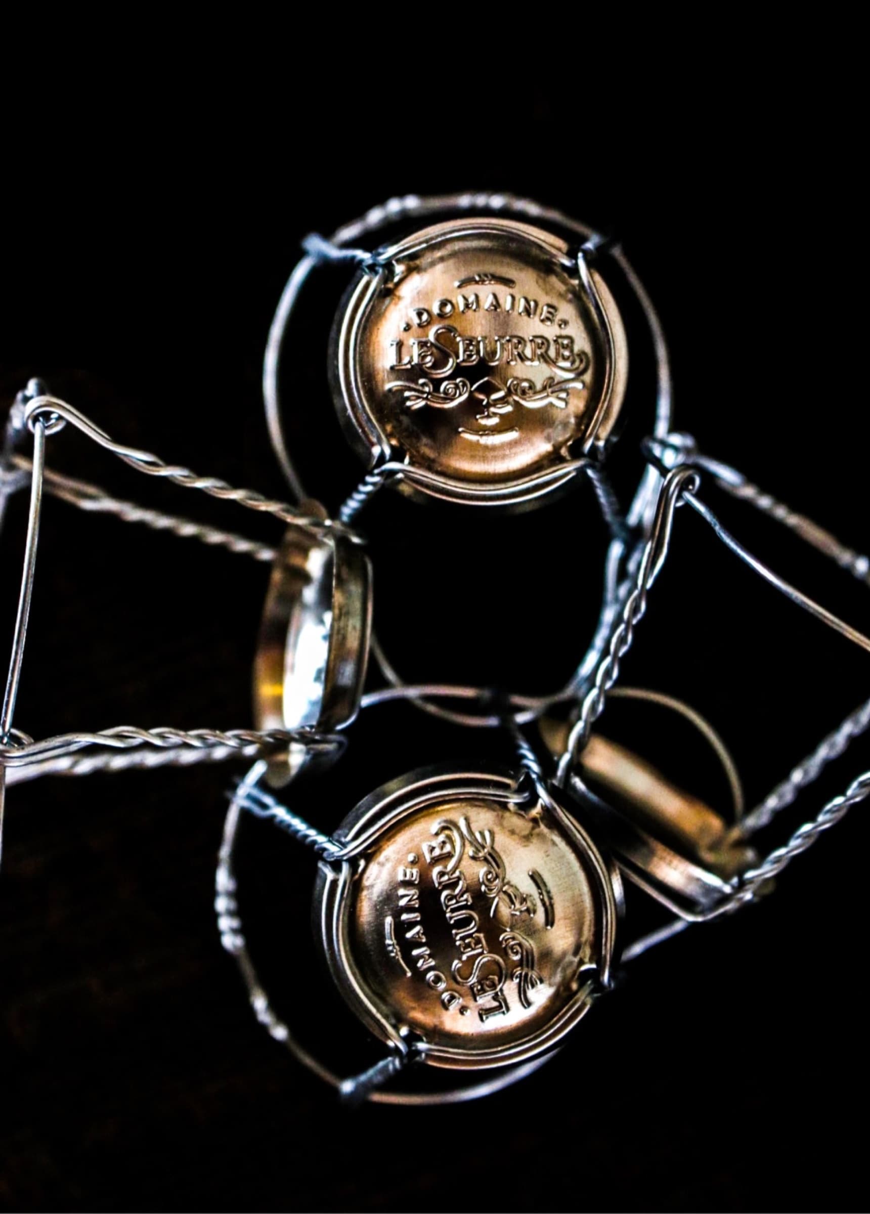 Engraved gold wire cages of Domaine LeSeurre sparkling bottles.